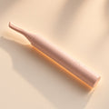 Halo blush-pink heated lash curler on a seamless cream backdrop in warm window light