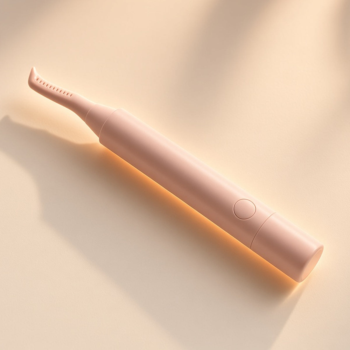 Halo blush-pink heated lash curler on a seamless cream backdrop in warm window light